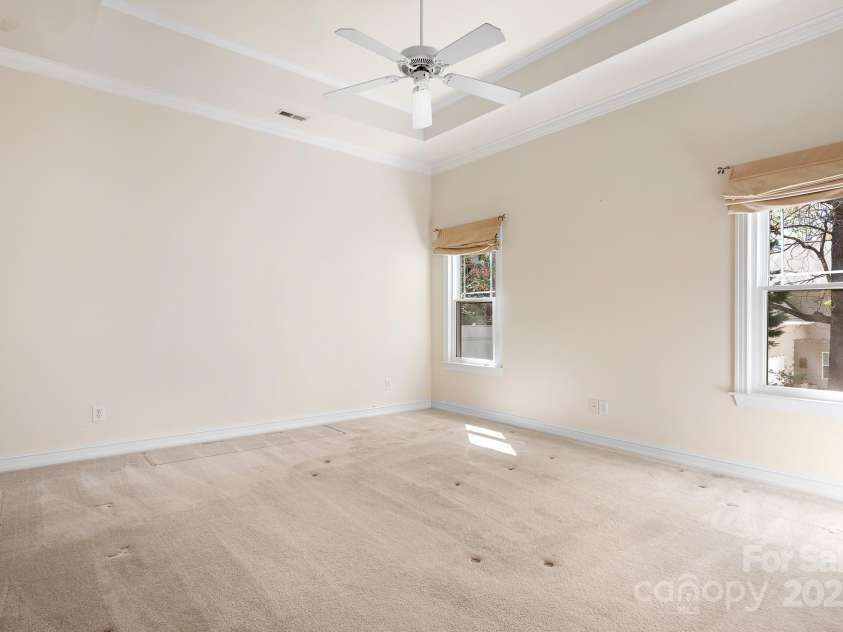 19221 Coachmans Trace, Cornelius, NC 28031.  MLS# CAR4241031, YatesRealty ID 10121. Primary bedroom with a tray ceiling and 2 windows for good natural light. Spacious and has primary ensuite bath