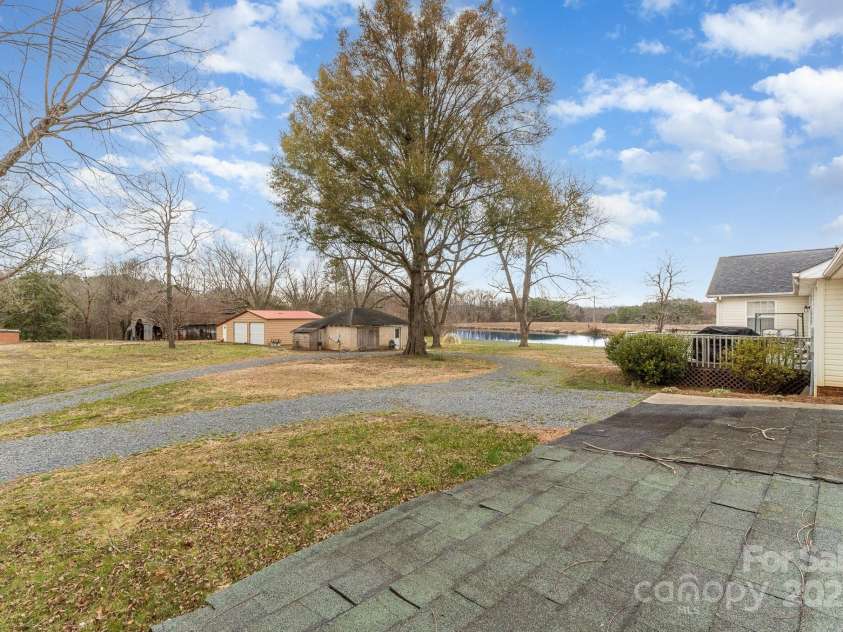 24697 Ramsey Drive, Albemarle, NC 28001.  MLS# CAR4227470, YatesRealty ID 10321. Backyard View With Gravel Drive Way and Pond View