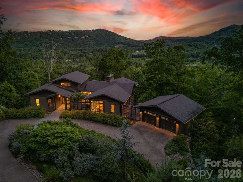 1121 Timberbluff Way, Arden, NC 28704.  MLS# CAR4389216, YatesRealty ID 10325. Twilight view showcasing the home's dramatic setting and architectural presence