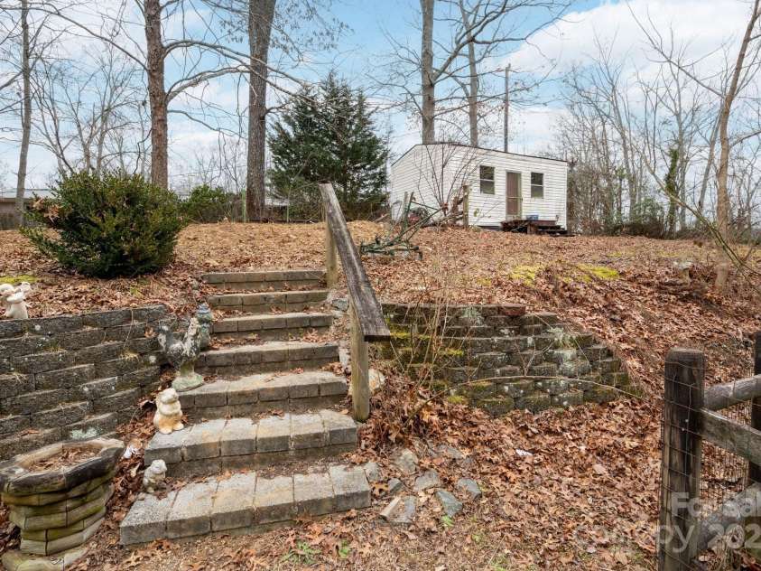 242 Breezy Mountain Lane, Mills River, NC 28759.  MLS# CAR4215866, YatesRealty ID 10330. Steps lead to upper back yard storage or artist shed.