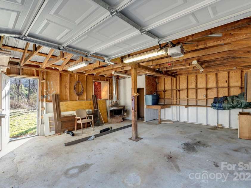 4 Morgan Cove Road, Candler, NC 28715.  MLS# CAR3898041, YatesRealty ID 11057. Oversized garage with woodstove, storage closet and workspace.