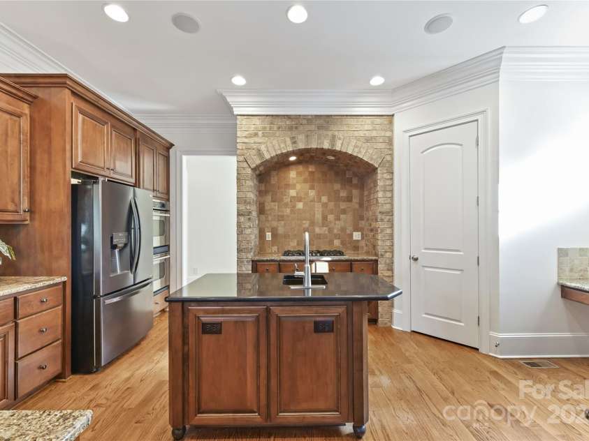 7295 Three Sisters Lane, Concord, NC 28027.  MLS# CAR4239485, YatesRealty ID 11233. Gourmet, Chef's Kitchen features granite counters, island, stainless steel appliances including double oven, gas cook top, tile back splash, desk area, walk in pantry & bar area!