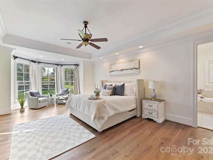 7295 Three Sisters Lane, Concord, NC 28027.  MLS# CAR4239485, YatesRealty ID 11233. Spacious Primary Suite on main level with tray ceiling, crown molding, bay window, recessed lights, hardwood floors, private bath & walk in closet!