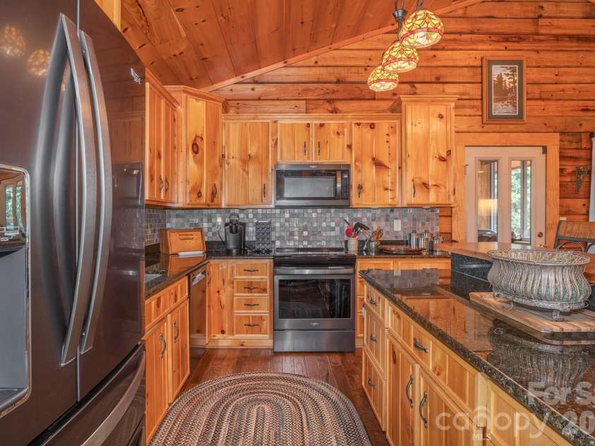 153 Brandy Ridge, Brevard, NC 28712.  MLS# CAR4366624, YatesRealty ID 11352. Kitchen Workspace & CabinetryFunctional kitchen layout featuring custom wood cabinetry, granite countertops, stainless steel appliances, and ample preparation space.