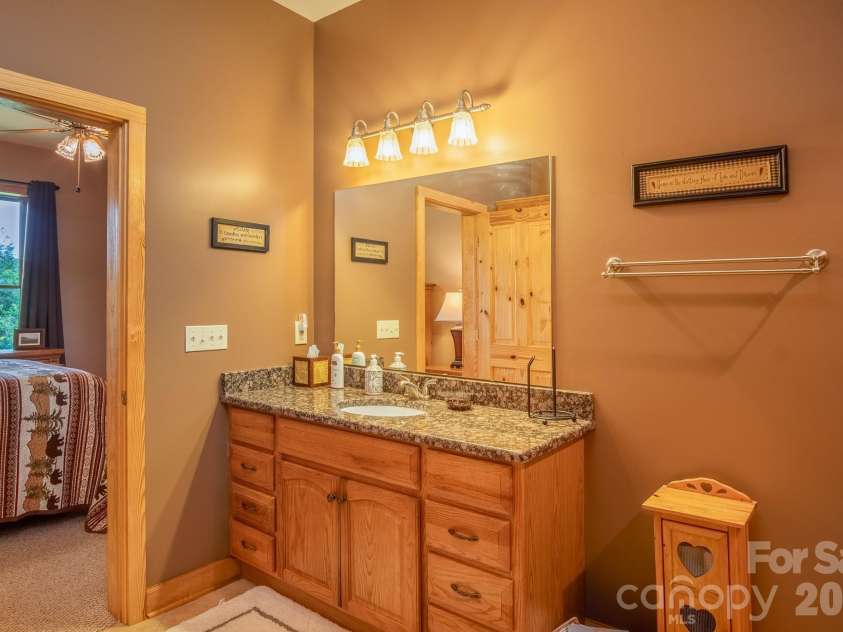 153 Brandy Ridge, Brevard, NC 28712.  MLS# CAR4366624, YatesRealty ID 11352. Lower-Level Ensuite Bath VanitySpacious ensuite bathroom featuring granite countertops, generous cabinetry, and a large vanity area.