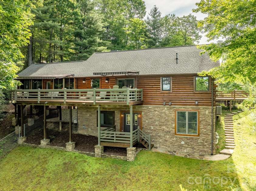 153 Brandy Ridge, Brevard, NC 28712.  MLS# CAR4366624, YatesRealty ID 11352. Rear Exterior – Elevated Drone PerspectiveAerial view showcasing the home's impressive rear elevation, expansive upper deck, lower-level outdoor access, and private wooded setting that defines mountain living.