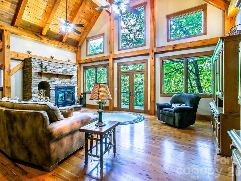 58 Great Aspen Way, Black Mountain, NC 28711.  MLS# CAR4366858, YatesRealty ID 11545. Beautiful, light-filled open concept living area with year-round mountain view, vaulted ceiling, adjacent deck, large windows bringing the outdoors indoors, and wood-burning fireplace. 