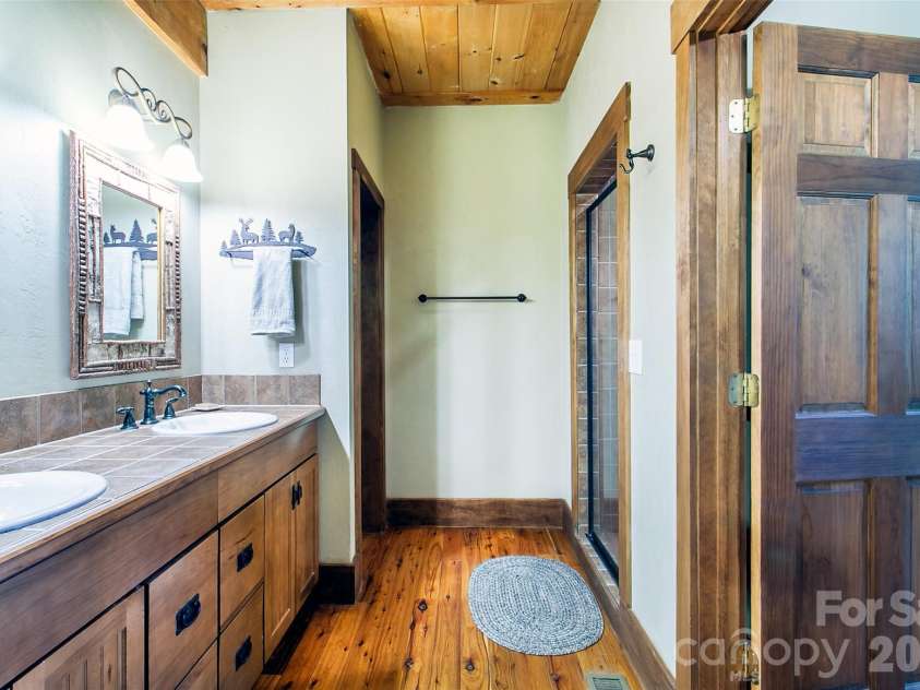 58 Great Aspen Way, Black Mountain, NC 28711.  MLS# CAR4366858, YatesRealty ID 11545. The primary bathroom has twin vanities, a water closet, linen shelves, and a gorgeous walk-in fully tiled shower with sitting bench.