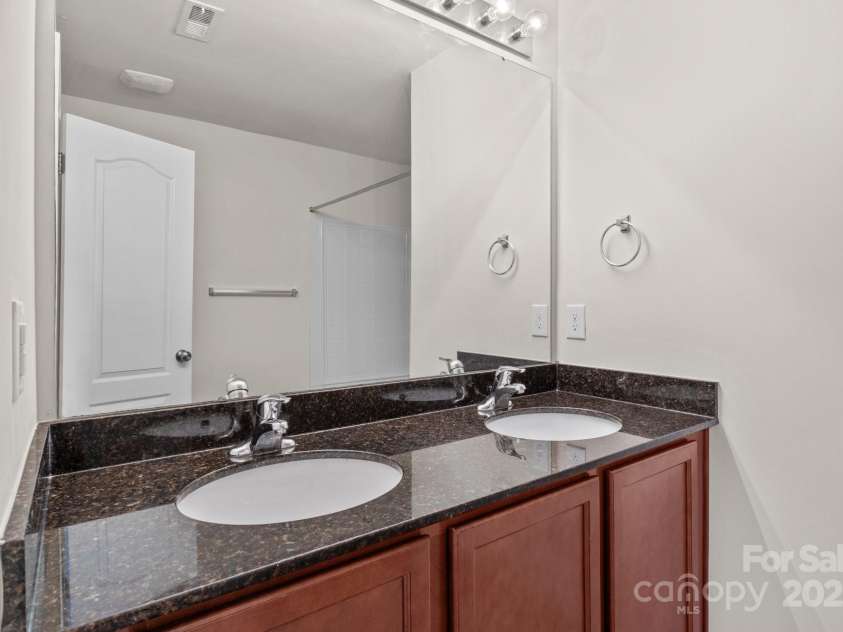 12550 McGrath Drive, Charlotte, NC 28269.  MLS# CAR4242569, YatesRealty ID 11597. Enjoy this stylish primary bathroom, equipped with a double vanity and granite countertop!