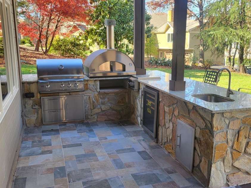 377 Riverwood Road, Mooresville, NC 28117.  MLS# CAR4192992, YatesRealty ID 11616. Brand new tiled patio with outdoor kitchen featuring Blaze Professional gas grill, pizza oven, stovetop burner, beverage refrigerator, and sink all surrounded by granite counters and stone-surround.