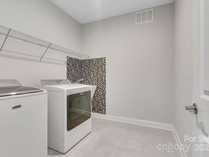 8210 Festival Way, Charlotte, NC 28215.  MLS# CAR4324351, YatesRealty ID 11707. A generous-sized Laundry Room (with Washer & Dryer included) has tile floors and a free-standing laundry sink with a custom decorative tile surround. 