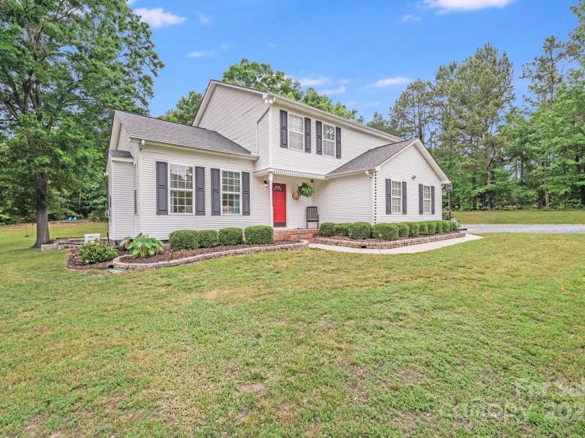 6910 Birdsong Lane, Waxhaw, NC 28173.  MLS# CAR4253788, YatesRealty ID 11745. Pretty white farmhouse with rain cups and neat landscaping surrounding the home