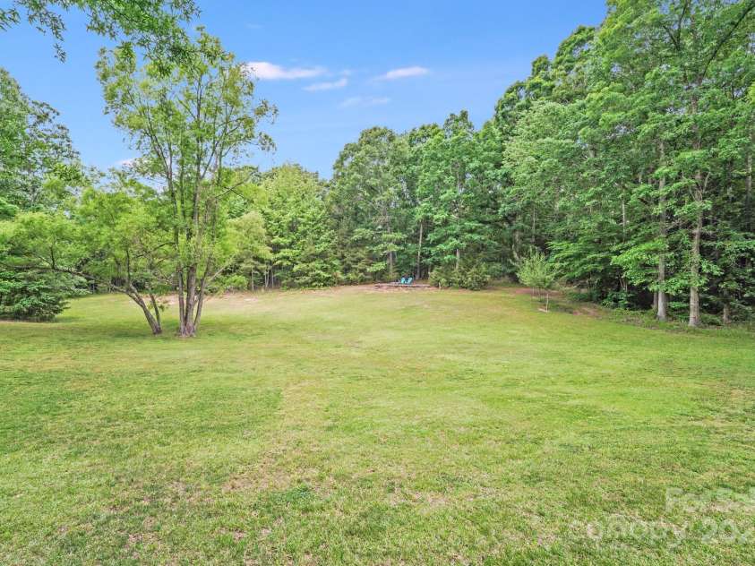 6910 Birdsong Lane, Waxhaw, NC 28173.  MLS# CAR4253788, YatesRealty ID 11745. The expansive backyard offers wide-open views and acres of lush green grass—perfect for play, pasture, or peaceful relaxation. Tucked into this serene landscape is a moon deck with a built-in fire pit