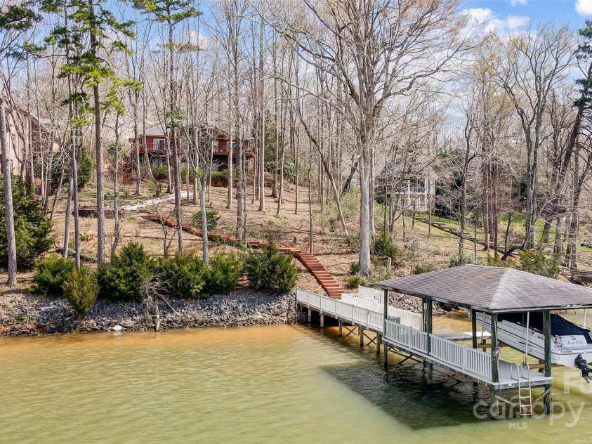 4633 River Bluff Court, Charlotte, NC 28214.  MLS# CAR4235344, YatesRealty ID 11796. The outdoor oasis is an entertainer’s dream featuring a massive deck, covered patio, lush landscaping, lake deck, & covered dock w/boat lift, perfect for all your boating adventures