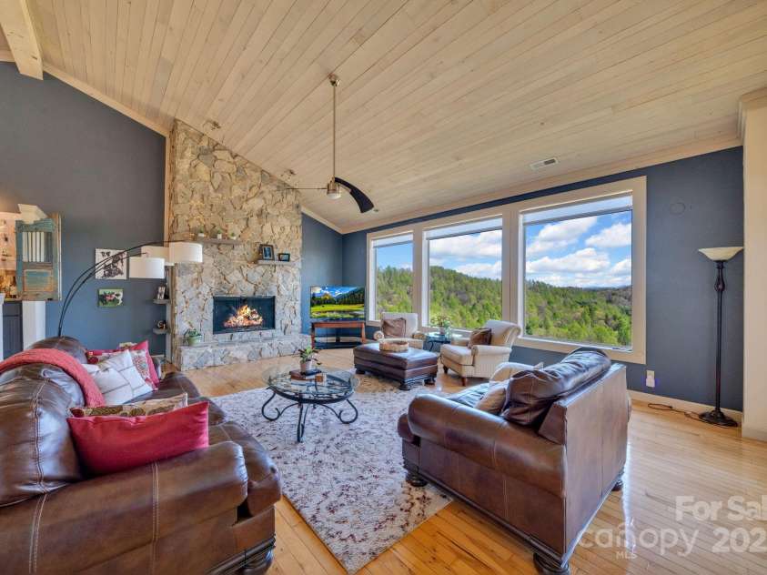 246 Pinnacle Mountain Road, Zirconia, NC 28790.  MLS# CAR4249618, YatesRealty ID 12104. View looking out the back of the home at the long range mountains, gas fireplace, wetbar to the left of the fireplace, valuted ceilings, open floor plan, wood floors