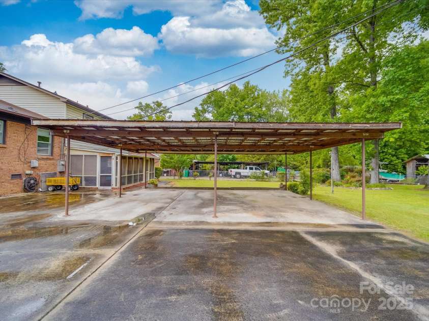 2213 Milton Road, Charlotte, NC 28215.  MLS# CAR4255190, YatesRealty ID 12108. A three car accommodating car shelter is in good condition and helps to act as a great place to turn around on the abundance of concrete paved parking off the rear