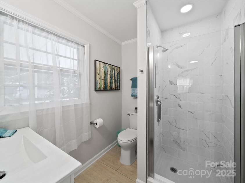 2213 Milton Road, Charlotte, NC 28215.  MLS# CAR4326281, YatesRealty ID 12108. Primary bath on the lower level boasts a lovely tiled shower with custom glass