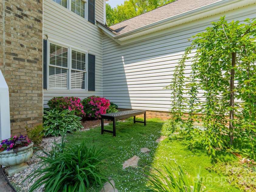 228 Red Dog Drive, Mooresville, NC 28115.  MLS# CAR4245955, YatesRealty ID 12253. A meditation bench among the quaint landscaping outside the front door