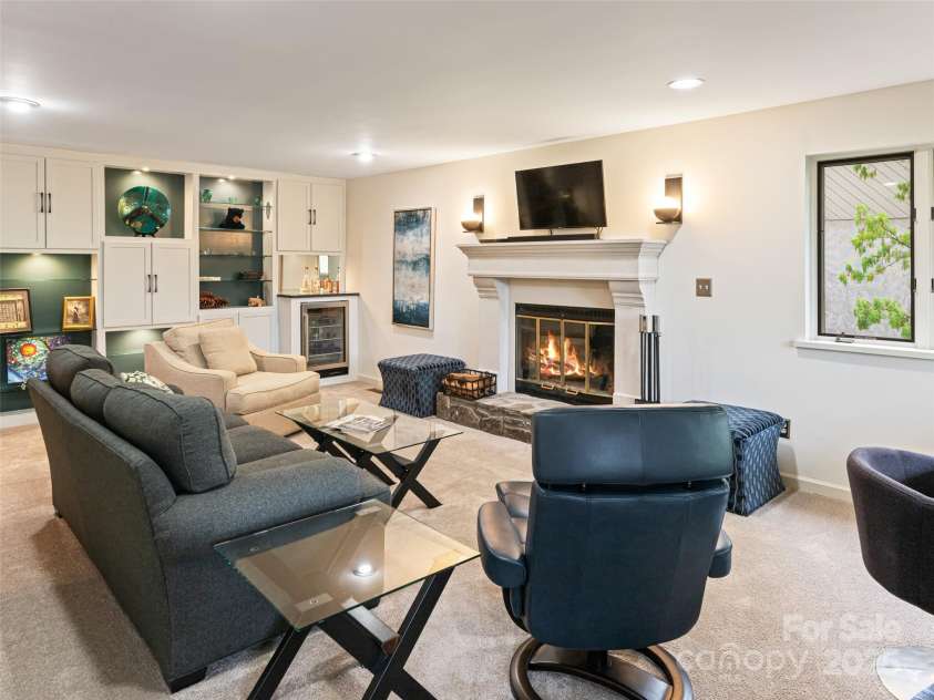 1901 Timber Trail, Asheville, NC 28804.  MLS# CAR4252207, YatesRealty ID 12288. Spacious light-filled lower level family room with gas fireplace and mantel. Custom built-in bookcase with lighting and glass shelving. Beverage refrigerator.Beverage Refrigerator.