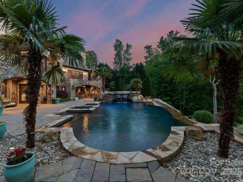 172 Tennessee Circle, Mooresville, NC 28117.  MLS# CAR4252701, YatesRealty ID 1230. Infinity-edge pool with waterfall and integrated spa, surrounded by stone decking.