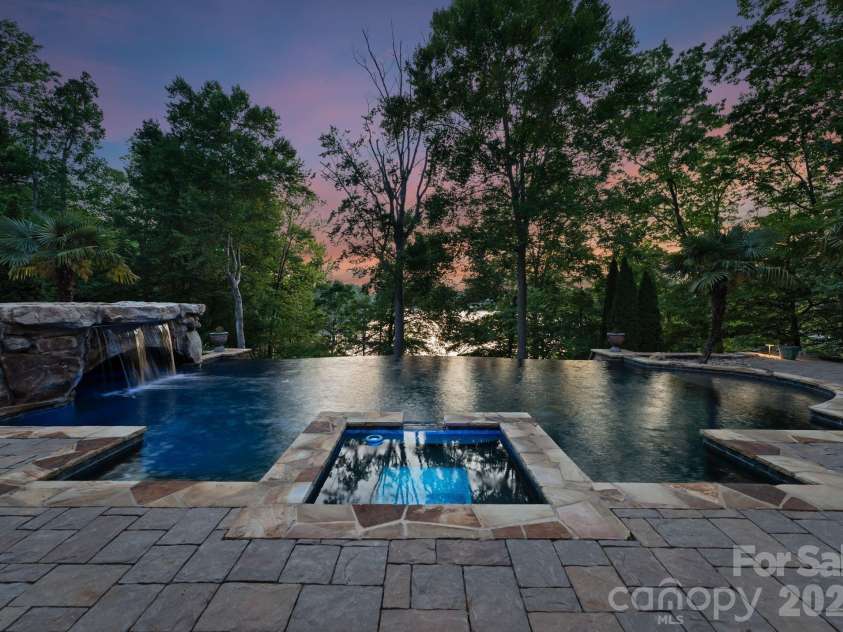 172 Tennessee Circle, Mooresville, NC 28117.  MLS# CAR4252701, YatesRealty ID 1230. Infinity-edge pool with waterfall and integrated spa, surrounded by stone decking.