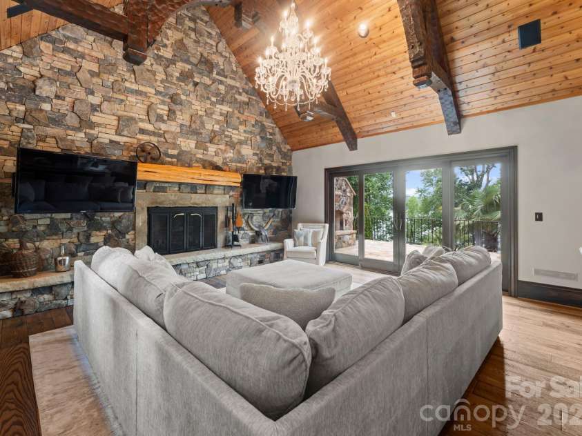 172 Tennessee Circle, Mooresville, NC 28117.  MLS# CAR4252701, YatesRealty ID 1230. Living Room with stone fireplace, dual TVs, and doors to outdoor patio.