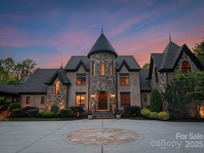 172 Tennessee Circle, Mooresville, NC 28117.  MLS# CAR4252701, YatesRealty ID 1230. Pass through a private gate to arrive at this grand stone residence, where a nautical star design anchors the front driveway. A stately façade with arched entry and manicured landscaping warmly welcomes you home.