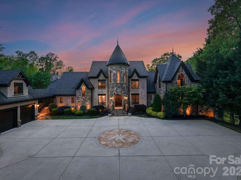 172 Tennessee Circle, Mooresville, NC 28117.  MLS# CAR4252701, YatesRealty ID 1230. Pass through a private gate to arrive at this grand stone residence, where a nautical star design anchors the front driveway. A stately façade with arched entry and manicured landscaping warmly welcomes you home.