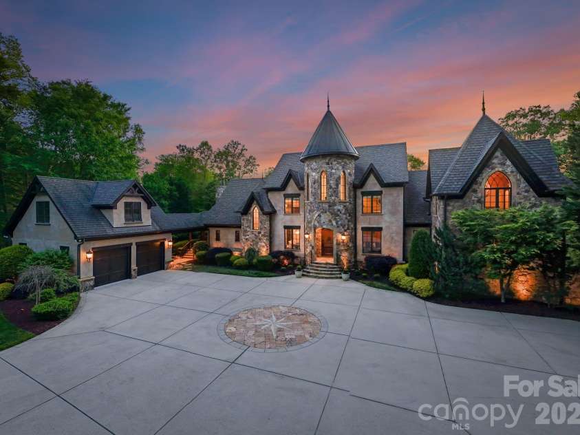 172 Tennessee Circle, Mooresville, NC 28117.  MLS# CAR4252701, YatesRealty ID 1230. Pass through a private gate to arrive at this grand stone residence, where a nautical star design anchors the front driveway. A stately façade with arched entry and manicured landscaping warmly welcomes you home.