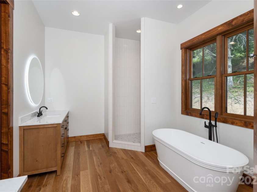 750 Silver Springs Drive, Banner Elk, NC 28604.  MLS# CAR4160928, YatesRealty ID 1238. Main floor primary suite with incredible mountain views, access to porch & 2 walk-in closets. Primary bathroom with double vanities & backlit mirrors, soaking bathtub, shower & water closet.