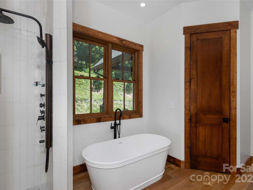 750 Silver Springs Drive, Banner Elk, NC 28604.  MLS# CAR4160928, YatesRealty ID 1238. Main floor primary suite with incredible mountain views, access to porch & 2 walk-in closets. Primary bathroom with double vanities & backlit mirrors, soaking bathtub, shower & water closet.