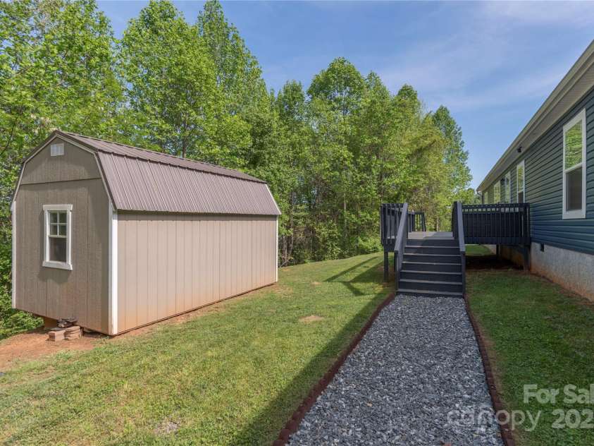 87 Horseback Lane, Marshall, NC 28753.  MLS# CAR4251023, YatesRealty ID 12384. View from the fire pit back toward the front deck and rear of storage building.