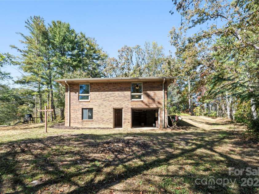 90 Joe Jenkins Road, Fairview, NC 28730.  MLS# CAR4288516, YatesRealty ID 12466. Exterior view of the side of the house,  showcasing both the walk-out door and the basement garage door.  