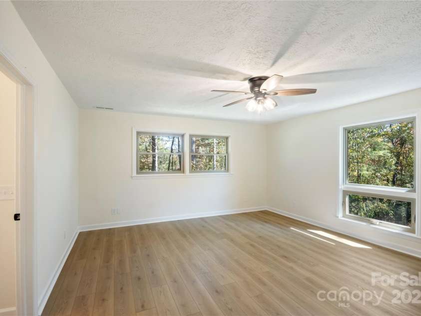 90 Joe Jenkins Road, Fairview, NC 28730.  MLS# CAR4288516, YatesRealty ID 12466. This primary suite is a true oasis, boasting an abundance of natural light that streams in throughout the day. The space has been thoughtfully designed with a modern, updated luxury bathroom, offering a tranquil and rej