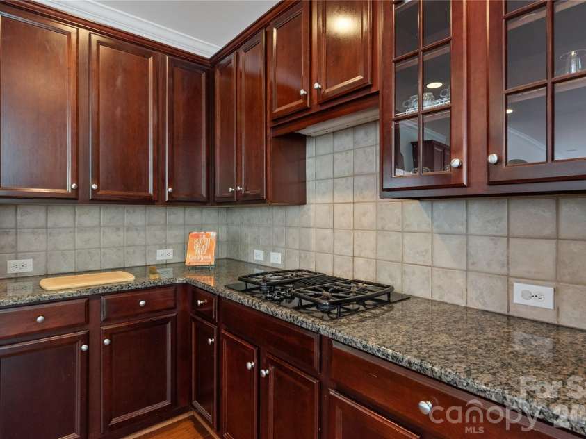 8914 Landsdowne Avenue, Harrisburg, NC 28075.  MLS# CAR4259422, YatesRealty ID 1276. Kitchen showing the tile backsplash and marble counters.  Plenty of space to store and show your favorite glass ware