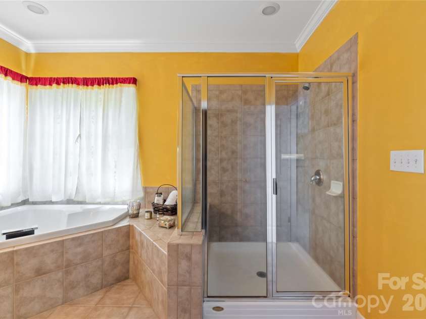 8914 Landsdowne Avenue, Harrisburg, NC 28075.  MLS# CAR4259422, YatesRealty ID 1276. Primary bath with walk in extended shower and a tub with a waterfall faucet.