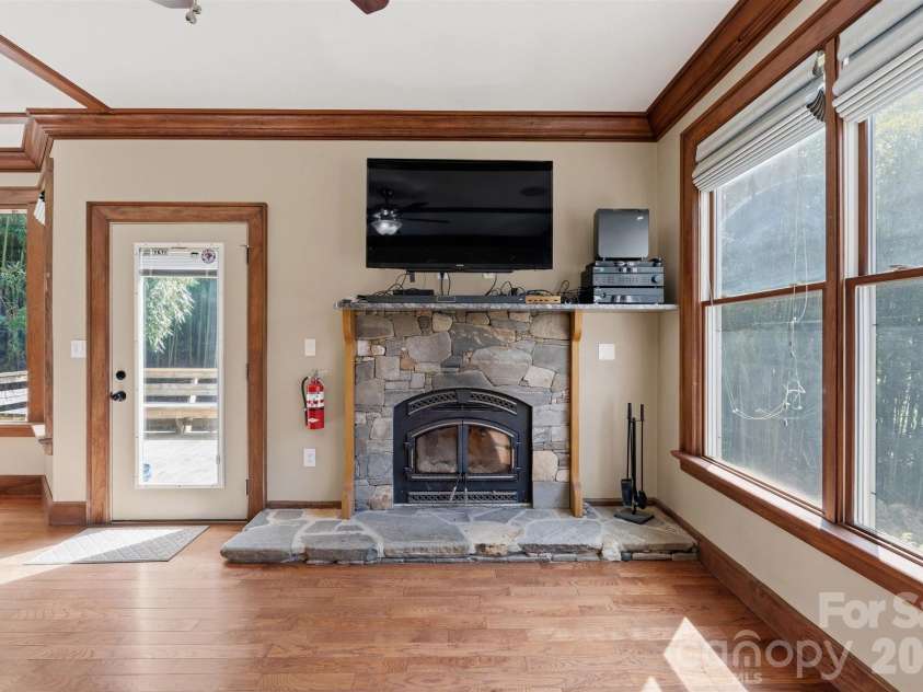 22 Pear Tree Lane, Leicester, NC 28748.  MLS# CAR4371027, YatesRealty ID 12806. Highly efficient woodburning insert with blower is framed by custom river rock.