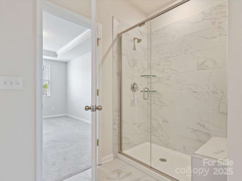 3813 Amalia Place, Indian Land, SC 29707.  MLS# CAR4246224, YatesRealty ID 12822. Main Level Primary ensuite Bathroom features a walk in shower with seating & luxury tiled wall.