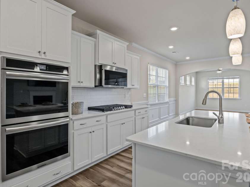 4840 Maiden Creek Way, Maiden, NC 28650.  MLS# CAR4367470, YatesRealty ID 12836. Full view from kitchen to breakfast area with custom moldings, through arched entryway into dining/keeping room.  Notice the clerestory windows which give light yet provide privacy.  Entry door to the fully screened, co