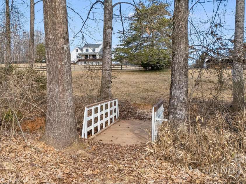 169 Stoneybrook Way, Tryon, NC 28782.  MLS# CAR4217213, YatesRealty ID 1286. Bridge crosses over small creek to the back half of yard and FETA trail.