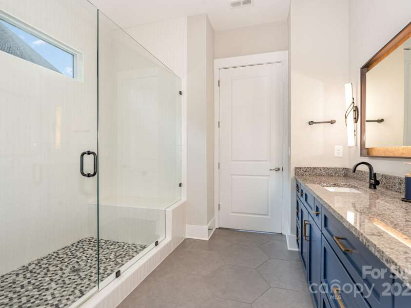 21016 Molly Harper Drive, Cornelius, NC 28031.  MLS# CAR4320388, YatesRealty ID 12915. Frameless glass surround and custom tilework and bench, plus a transom window provides natural light while maintaining privacy