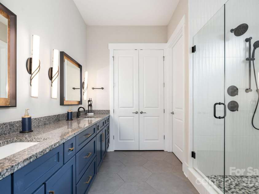 21016 Molly Harper Drive, Cornelius, NC 28031.  MLS# CAR4320388, YatesRealty ID 12915. Primary bath is stunning with an oversized shower featuring large format tile surround. LED mirrors and plenty of cabinet space make this an easy to navigate space. Also, note the large linen closet as well as pri