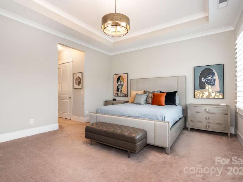 21016 Molly Harper Drive, Cornelius, NC 28031.  MLS# CAR4320388, YatesRealty ID 12915. The primary bedroom features a stacked tray ceiling with crown molding and large windows with plantation shutters overlooking the rear yard
