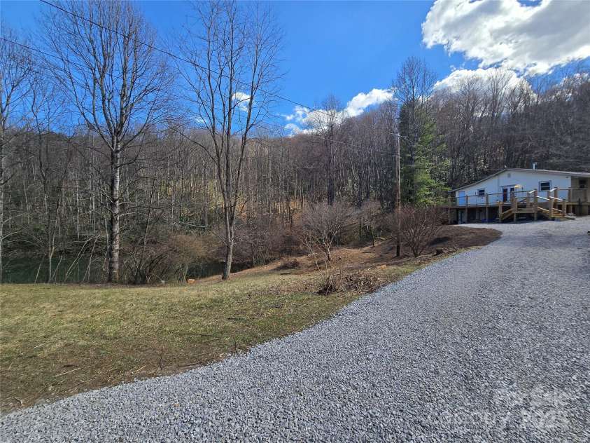 59 Upper Saw Branch Road, Candler, NC 28715.  MLS# CAR4226917, YatesRealty ID 13059. Driveway, pond, and front of house