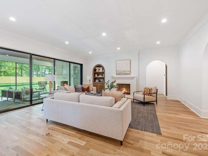 5601 Robinhood Road, Charlotte, NC 28211.  MLS# CAR4258800, YatesRealty ID 13109. Great Room with gas fireplace and sliding doors out to the screen porch.  The arched doorway leads to the Primary Suite