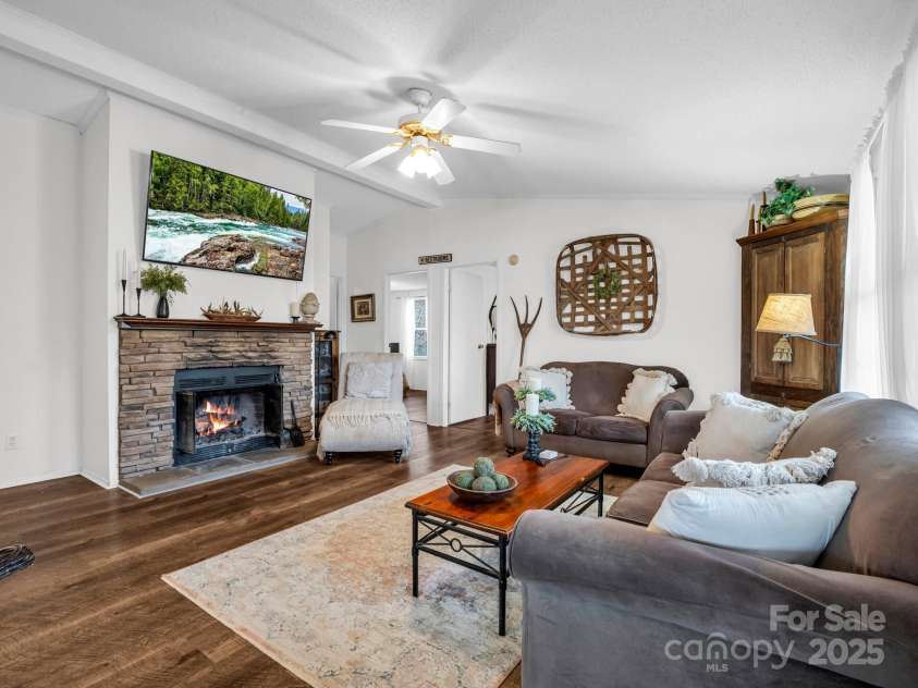 243 Buffalo Creek Road, Lake Lure, NC 28746.  MLS# CAR4219032, YatesRealty ID 13241. The living room in this updated split-floor plan home boasts luxury vinyl flooring throughout, wood buring fireplace, 3 bedrooms, 2 full bathrooms, huge kitchen and laundry room all on 2 peaceful, wooded parcels, bo