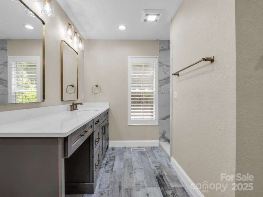 197 Hawthorne Drive, Lake Lure, NC 28746.  MLS# CAR4154813, YatesRealty ID 133. Second of two vanities in the primary ensuite bathroom, complete with walk-in shower, California Closet system, and laundry room with front-loading washer and dryer.