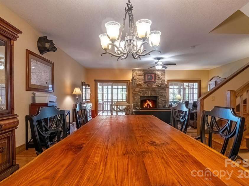 620 Sapphire Valley Road, Cashiers, NC 28717.  MLS# CAR4329121, YatesRealty ID 1359. Looking from the kitchen towards the fireplace, thru the breakfast bar opening, across the dining area, to the Sliders of the rear covered wooden deck. Dining table and chairs convey. Hutch on the left, matches the 