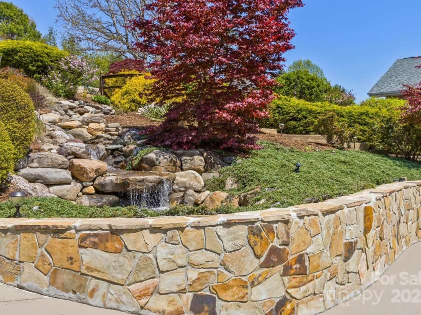 22 Valley Drive, Weaverville, NC 28787.  MLS# CAR4244497, YatesRealty ID 13599. Stone wall at front garden & waterfall/pond
