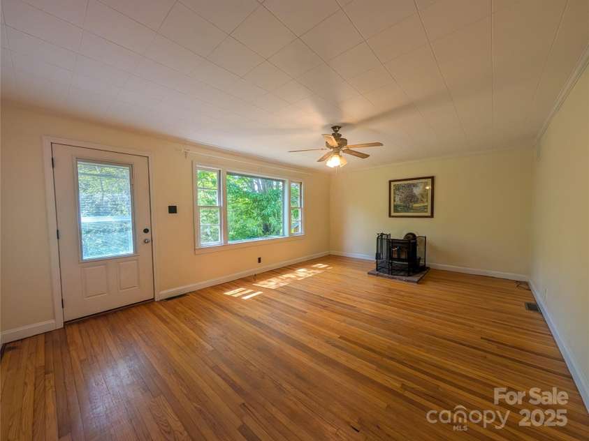 95 Lady Bug Lane, Burnsville, NC 28714.  MLS# CAR4206406, YatesRealty ID 13600. Living area with large picture window to enjoy natural lighting and wood burning fireplace for alternative heating source